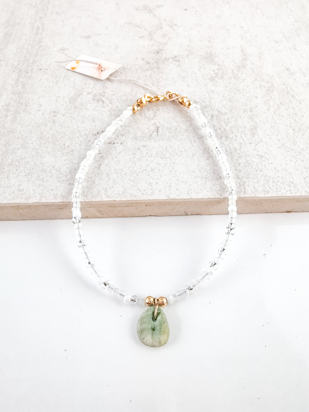 Glass bead bracelet with a green stone pendant